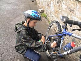 Harry oils his chain with Michael's cycle oil outside Bellever Youth Hostel